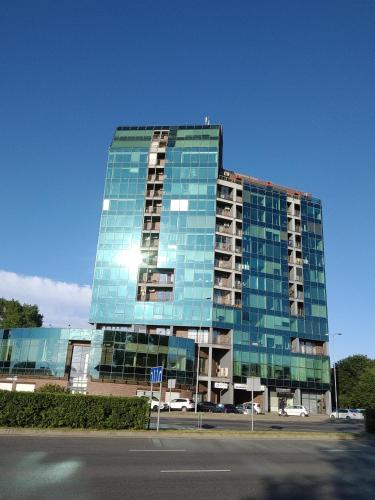 a tall glass building with the sun shining on it at Apartaments near Švyturio arena in Klaipėda