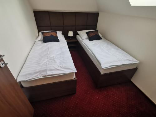 two twin beds in a small room with red carpet at Termál Apartmanház in Veresegyház