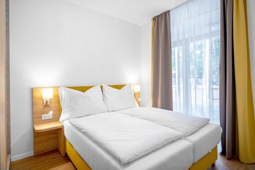 ein Schlafzimmer mit einem Bett und einem großen Fenster in der Unterkunft Szent Bernadett Családi Apartmanház in Siófok