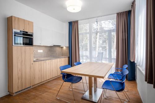 uma cozinha com uma mesa de madeira e cadeiras azuis em Szent Bernadett Családi Apartmanház em Siófok