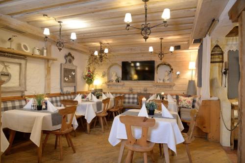 a restaurant with white tables and chairs and a tv at Märchenwald Steiermark Gasthof Sonnenhof in Sankt Georgen ob Judenburg