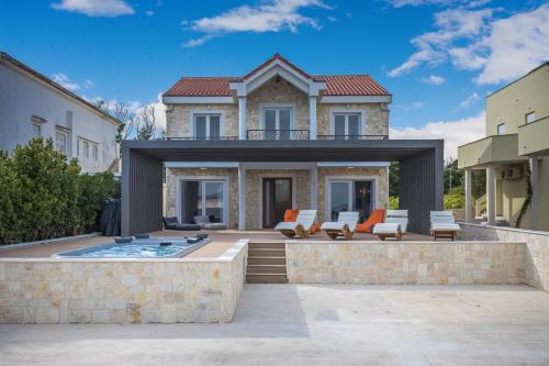 a house with a patio and a swimming pool at VILLA FUX ZRCE Novalja - direkt am Strand in Časka