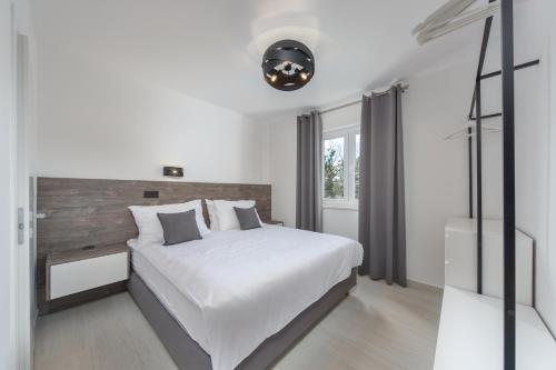 a white bedroom with a large bed and a window at VILLA FUX ZRCE Novalja - direkt am Strand in Časka