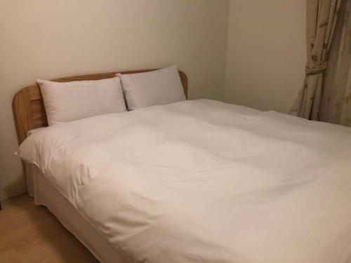 a bed with white sheets and pillows in a bedroom at Jiufen Gourd Stone TreeHouse 137 in Ruifang