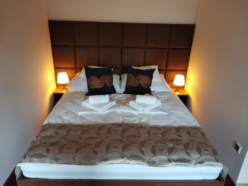 a bedroom with a large bed with two lamps at Termál Apartmanház in Veresegyház