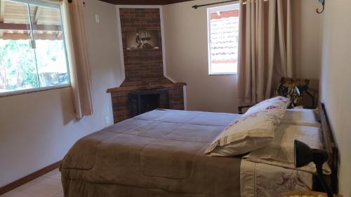 1 dormitorio con 1 cama grande y chimenea en Casa do Osorio, en Visconde De Maua