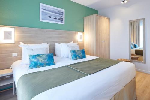 a bedroom with a large white bed with blue pillows at Les Terrasses d'Atlanthal in Anglet