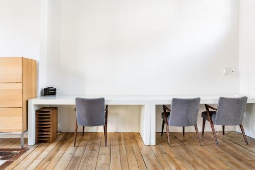 a white table with four chairs in a room at PAKHUIS in Ghent