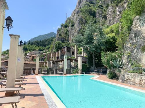 a swimming pool with chairs and a mountain at Hotel Castell - Montagnoli Group in Limone sul Garda