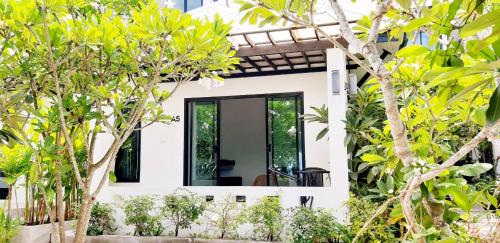 a white house with trees in front of it at Magic House - No Pets Allowed in Chumphon