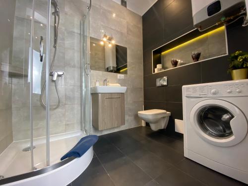 a bathroom with a shower toilet and a washing machine at P&J Apartamenty Grodzka in Kraków