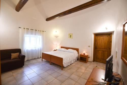 sypialnia z łóżkiem, kanapą i telewizorem w obiekcie Agriturismo il Ciliegeto w mieście Locorotondo