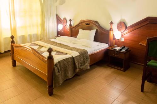 a bedroom with a large bed with a wooden headboard at Palm world Hotels Mbarara in Mbarara