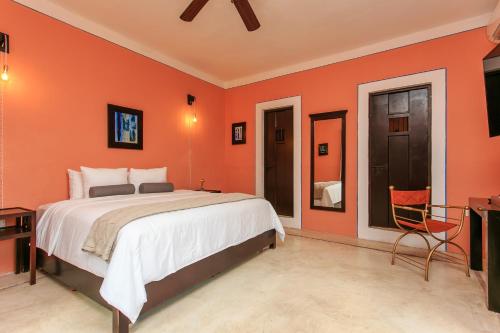 1 dormitorio con paredes de color naranja, 1 cama y TV en Art 64 Hotel Boutique - Adults Only, en Mérida