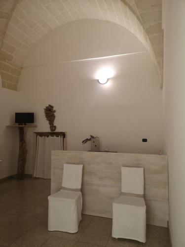 two white chairs in a white room with a table at B&B Corte San Giuseppe in Casarano