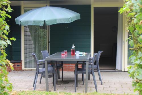 a table with chairs and an umbrella on a patio at Horsetellerie Rheezerveen in Hardenberg