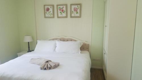 a bedroom with a white bed with two pictures on the wall at Summer Huahin Condo by Howard in Hua Hin