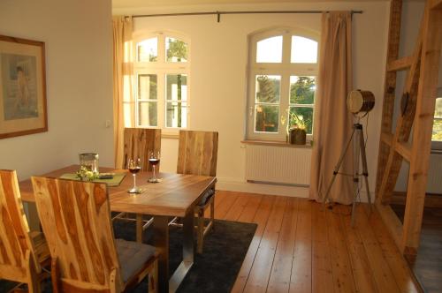 uma sala de jantar com uma mesa de madeira e janelas em Ferienwohnung ehemalige Revierförsterei "uns Lütt" em Kuhstorf