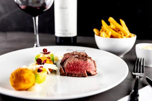 a plate of steak and french fries and a glass of wine at Alexander Hotel in Noordwijk aan Zee