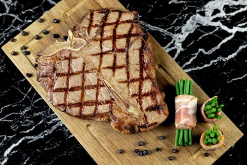 a wooden cutting board with a piece of meat and vegetables at Alexander Hotel in Noordwijk aan Zee