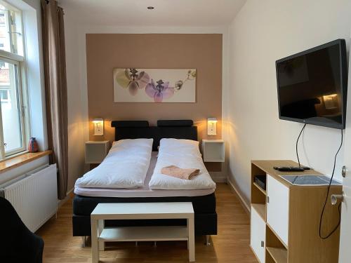a small bedroom with a bed and a tv at Davaa's Bed & Breakfast in Randers