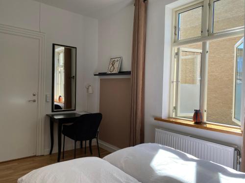 a bedroom with a bed and a desk and a window at Davaa's Bed & Breakfast in Randers