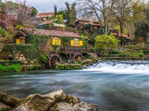 a house next to a river with a waterfall at Quinta de Real in Valença