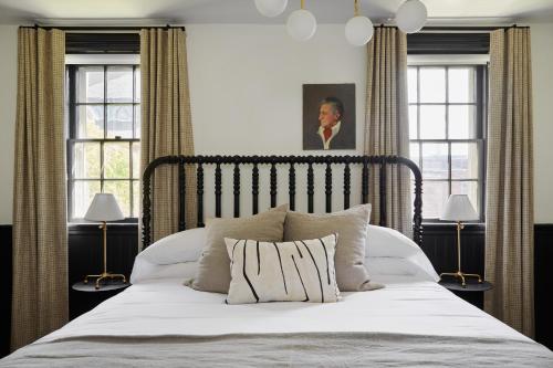 a bedroom with a large white bed with two windows at Blind Tiger Portland - Danforth Street Guest House in Portland