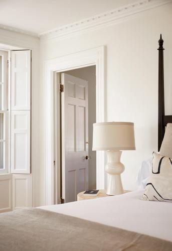a white bedroom with a bed and a lamp at Blind Tiger Portland - Danforth Street Guest House in Portland