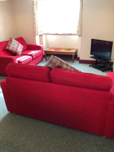 sala de estar con sofá rojo y mesa en Quayside Close Holiday Apartments, en Poole