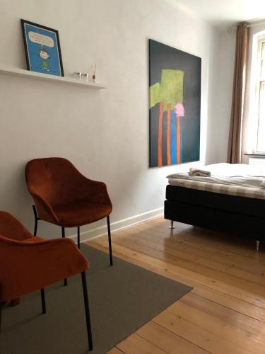 a bedroom with a bed and two chairs in it at Davaa's Bed & Breakfast in Randers