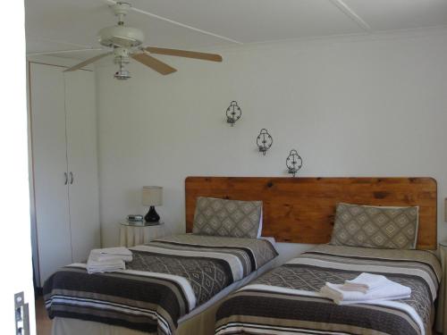 a bedroom with two beds and a ceiling fan at Wild Berry Guest Farm in Windy