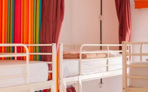 a room with two bunk beds and a rainbow curtain at Casa Grande Surf Hostel in El Médano