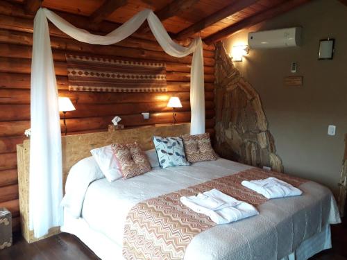 a bed in a log cabin with towels on it at Pualy Resort & Spa in Belén de Escobar