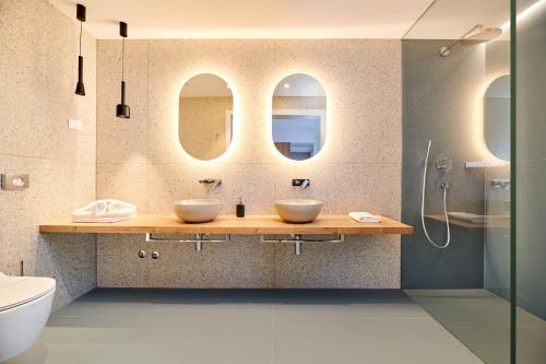 a bathroom with two sinks and two mirrors at Ribarska Koliba Resort in Pula