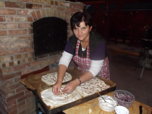a woman making pizzas in a brick oven at Hollókői Vendégház in Abaújszántó