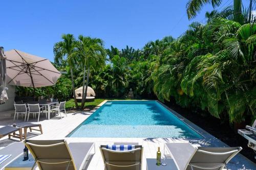 uma piscina com cadeiras e um guarda-sol em Paradise Home 3 BR with Heated Pool close to Beach em Fort Lauderdale