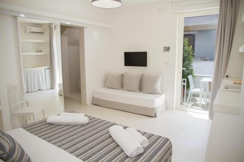 a white living room with a couch and a tv at Dimora Ausentum in Torre San Giovanni Ugento