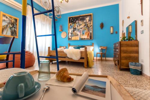 Boipeba Guesthouse في ألغيرو: غرفة نوم بجدران زرقاء وسرير مع طاولة