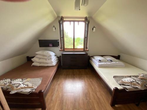 2 łóżka w pokoju na poddaszu z oknem w obiekcie Ignacówka w Kobylej Górze