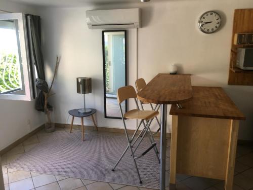una cucina con tavolo, sedie e orologio di T2 de la Bastide Rouge vue exceptionnelle (180°) sur Aix domaine privé T2 indépendant de 37 m2 avec terrasse exposée plein sud Piscine 10 X 5 ad Aix en Provence
