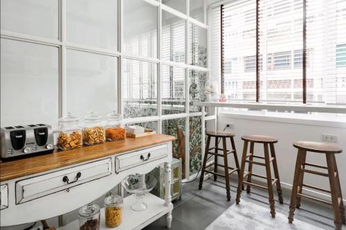 a kitchen with a counter with stools and windows at Hide and Seek Boutique Hometel in Bangkok