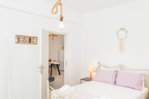a bedroom with white walls and a bed with pink pillows at Arsis Houses, Big House in Antiparos Town