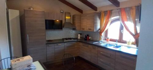 een keuken met houten kasten, een wastafel en een raam bij La scalinata del Borgo in Montecorvino Rovella