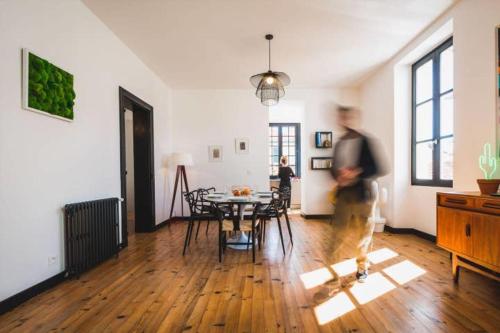 Un homme se promène dans un salon avec une table. dans l'établissement LONDON AVENUE KEYWEEK apartment Biarritz center with balcony and parking, à Biarritz