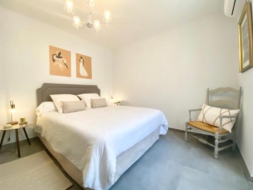 une chambre avec un grand lit blanc et une chaise dans l'établissement Cozy 2BR Appartment near the Port of Nice, à Nice