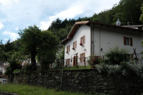a white house with a balcony on a stone wall at B&B La Tana Dei Ricci in Sestola