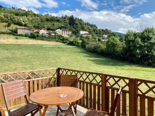 a wooden table and chairs on a balcony with a field at Apartamentos Alquitara in Potes