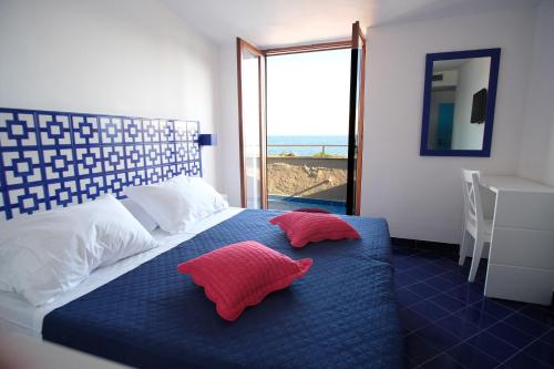 a bedroom with a bed with two red pillows on it at Hotel Baia Di Puolo in Massa Lubrense