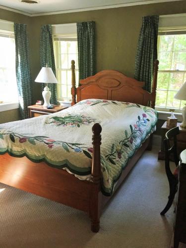 a bedroom with a wooden bed with a quilt on it at English Cottage in Greensboro